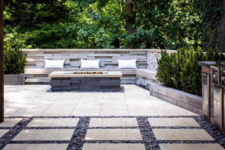 For this project, the beige Travertina slabs, the beige Graphix retaining wall system, the faux-wood Borealis collection (BBQ island and the pool borders) were used in this backyard to create a full entertainment living space. It includes a fire pit, a seating area, plus a dipping pool that falls into a full-size pool. Other outdoor elements, like water fountains and additional fire pits, were installed around the pool for a wow effect. These landscape stones blend perfectly well with nature's elements.