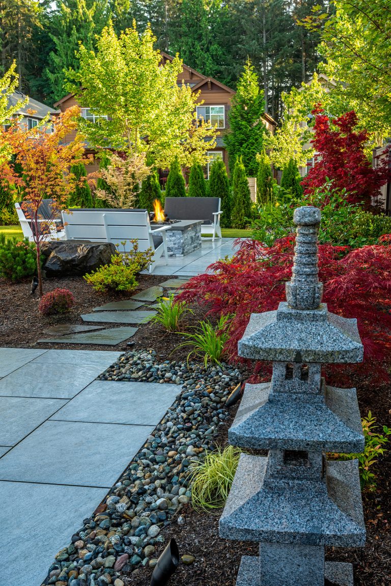 These clients' small yard had severe drainage issues, making it difficult for their large family to spend time outdoors. We worked with the clients to create several spaces in the small area that flowed together and met the family's needs. The modern-styled furniture spaces divided by flagstone pavers separated the spaces while an array of short plantings, Japanese maples, and Asian lantern decor introduced fluidity.