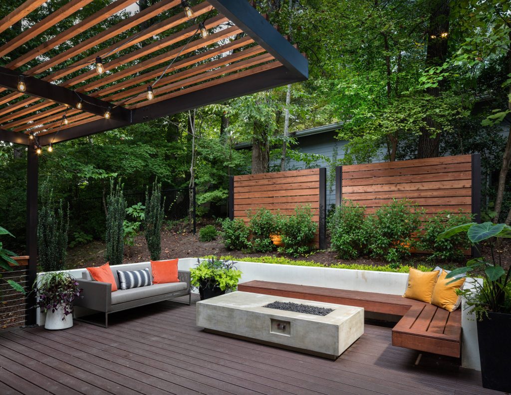 The upper level of this gorgeous Trex deck is the central entertaining and dining space and includes a beautiful concrete fire table and a custom cedar bench that floats over the deck. Light brown custom cedar screen walls provide privacy along the landscaped terrace and compliment the warm hues of the decking. Clean, modern light fixtures are also present in the deck steps, along the deck perimeter, and throughout the landscape making the space well-defined in the evening as well as the daytime.