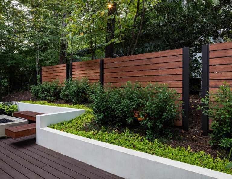 Light brown custom cedar screen walls provide privacy along the landscaped terrace and compliment the warm hues of the decking and provide the perfect backdrop for the floating wooden bench.
