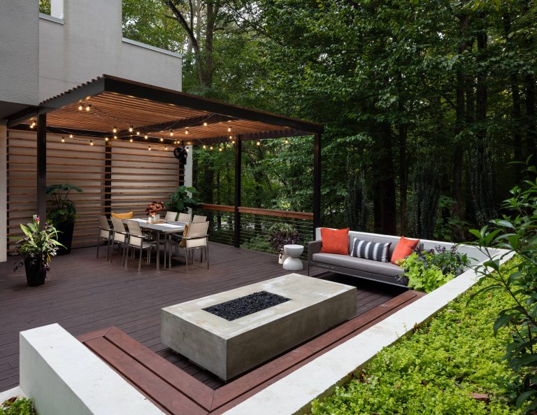The upper level of this gorgeous Trex deck is the central entertaining and dining space and includes a beautiful concrete fire table and a custom cedar bench that floats over the deck. The dining space is defined by the stunning, cantilevered, aluminum pergola above and cable railing along the edge of the deck. Adjacent to the pergola is a covered grill and prep space. Light brown custom cedar screen walls provide privacy along the landscaped terrace and compliment the warm hues of the decking. Clean, modern light fixtures are also present in the deck steps, along the deck perimeter, and throughout the landscape making the space well-defined in the evening as well as the daytime. by Boyce Design and Contracting | Fire Pits|Backyard Design|Outdoor Living Spaces|Landscape Design|Backyard Ideas|Landscaping|Landscaping Ideas|Landscape Installation|Fire Feautures|Fire Pit