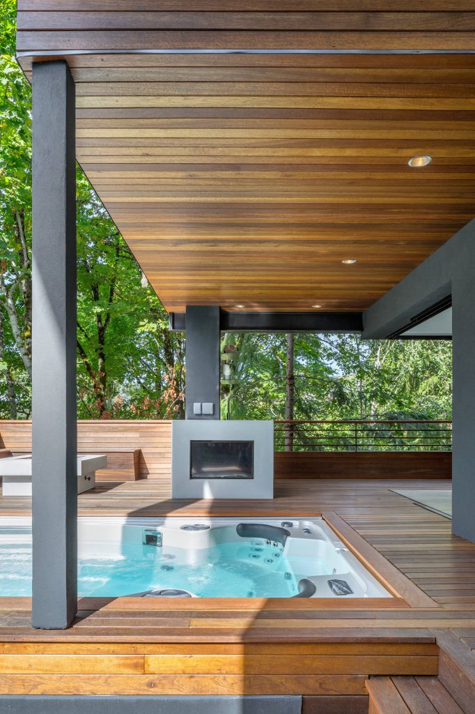 On the ground level we installed another indoor/outdoor space with built in TV, custom fire pit and therapeutic swim spa. The addition of a custom cement bar area with refrigerator and blackened steel custom shelving is accessed seamlessly from the family room via a fold-away open corner door system that stacks inside the walls.