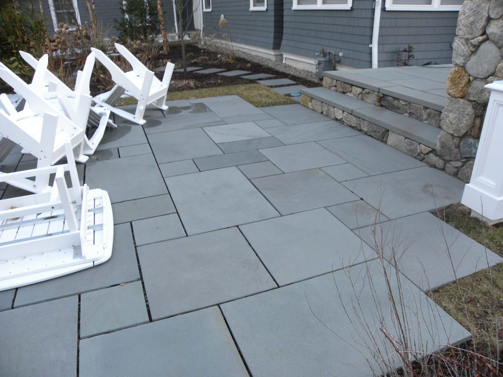 Example of a mid-sized classic backyard stone patio design in Boston with a fire pit and no cover