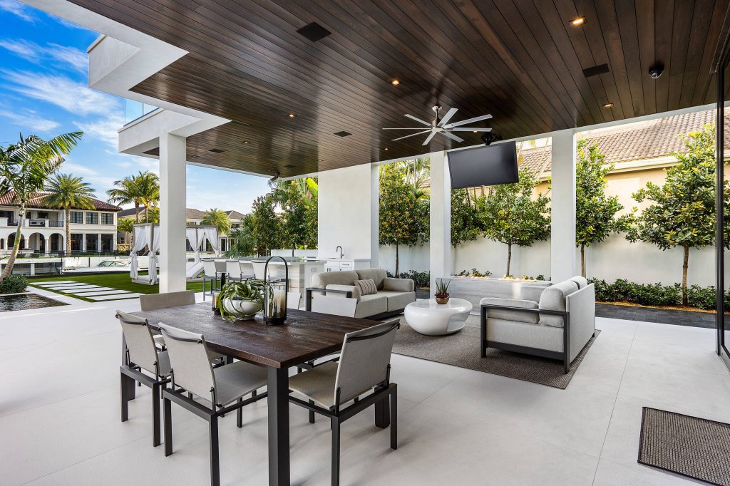 Infinity pool with outdoor living room, cabana, and two in-pool fountains and firebowls. Signature Estate featuring modern, warm, and clean-line design, with total custom details and finishes. The front includes a serene and impressive atrium foyer with two-story floor to ceiling glass walls and multi-level fire/water fountains on either side of the grand bronze aluminum pivot entry door. Elegant extra-large 47'' imported white porcelain tile runs seamlessly to the rear exterior pool deck, and a dark stained oak wood is found on the stairway treads and second floor. The great room has an incredible Neolith onyx wall and see-through linear gas fireplace and is appointed perfectly for views of the zero edge pool and waterway. The center spine stainless steel staircase has a smoked glass railing and wood handrail. Photo courtesy Royal Palm Properties