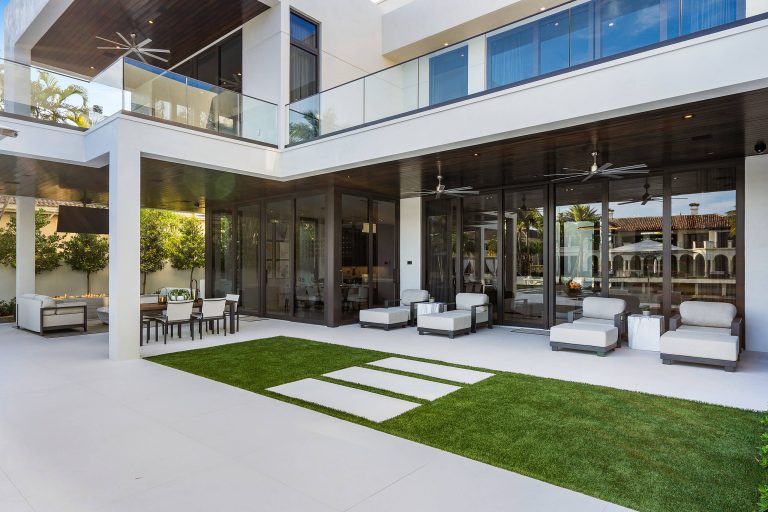 Infinity pool with outdoor living room, cabana, and two in-pool fountains and firebowls. Signature Estate featuring modern, warm, and clean-line design, with total custom details and finishes. The front includes a serene and impressive atrium foyer with two-story floor to ceiling glass walls and multi-level fire/water fountains on either side of the grand bronze aluminum pivot entry door. Elegant extra-large 47'' imported white porcelain tile runs seamlessly to the rear exterior pool deck, and a dark stained oak wood is found on the stairway treads and second floor. The great room has an incredible Neolith onyx wall and see-through linear gas fireplace and is appointed perfectly for views of the zero edge pool and waterway. The center spine stainless steel staircase has a smoked glass railing and wood handrail. Photo courtesy Royal Palm Properties