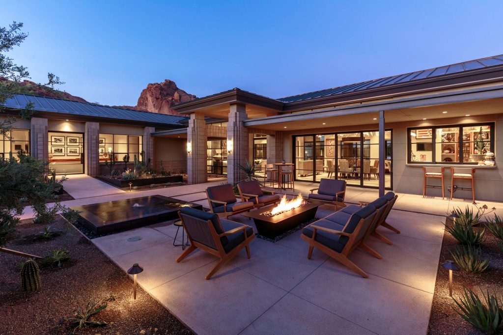This “Arizona Inspired” home draws on some of the couples’ favorite desert inspirations. The architecture honors the Wrightian design of The Arizona Biltmore, the courtyard raised planter beds feature labeled specimen cactus in the style of the Desert Botanical Gardens, and the expansive backyard offers a resort-style pool and cabana with plenty of entertainment space. Additional focal areas of landscape design include an outdoor living room in the front courtyard with custom steel fire trough, a shallow negative-edge fountain, and a rare “nurse tree” that was salvaged from a nearby site, sits in the corner of the courtyard – a unique conversation starter. The wash that runs on either side of the museum-glass hallway is filled with aloes, agaves and cactus. On the far end of the lot, a fire pit surrounded by desert planting offers stunning views both day and night of the Praying Monk rock formation on Camelback Mountain.Project Details: Landscape Architect: Greey|Pickett Architect: Higgins Architects Builder: GM Hunt Builders Landscape Contractor: Benhart Landscaping Interior Designer: Kitchell Brusnighan Interior Design Photography: Ian Denker by Greey Pickett | Fire Pits|Backyard Design|Outdoor Living Spaces|Landscape Design|Backyard Ideas|Landscaping|Landscaping Ideas|Landscape Installation|Fire Feautures|Fire Pit