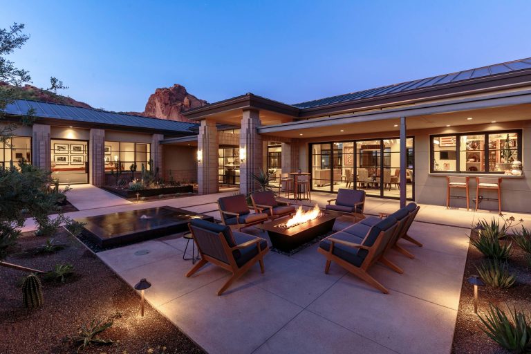 This “Arizona Inspired” home draws on some of the couples’ favorite desert inspirations. The architecture honors the Wrightian design of The Arizona Biltmore, the courtyard raised planter beds feature labeled specimen cactus in the style of the Desert Botanical Gardens, and the expansive backyard offers a resort-style pool and cabana with plenty of entertainment space. Additional focal areas of landscape design include an outdoor living room in the front courtyard with custom steel fire trough, a shallow negative-edge fountain, and a rare “nurse tree” that was salvaged from a nearby site, sits in the corner of the courtyard – a unique conversation starter. The wash that runs on either side of the museum-glass hallway is filled with aloes, agaves and cactus. On the far end of the lot, a fire pit surrounded by desert planting offers stunning views both day and night of the Praying Monk rock formation on Camelback Mountain.

Project Details:
Landscape Architect: Greey|Pickett
Architect: Higgins Architects
Builder: GM Hunt Builders
Landscape Contractor: Benhart Landscaping
Interior Designer: Kitchell Brusnighan Interior Design
Photography: Ian Denker
by Greey Pickett | Fire Pits|Backyard Design|Outdoor Living Spaces|Landscape Design|Backyard Ideas|Landscaping|Landscaping Ideas|Landscape Installation|Fire Feautures|Fire Pit