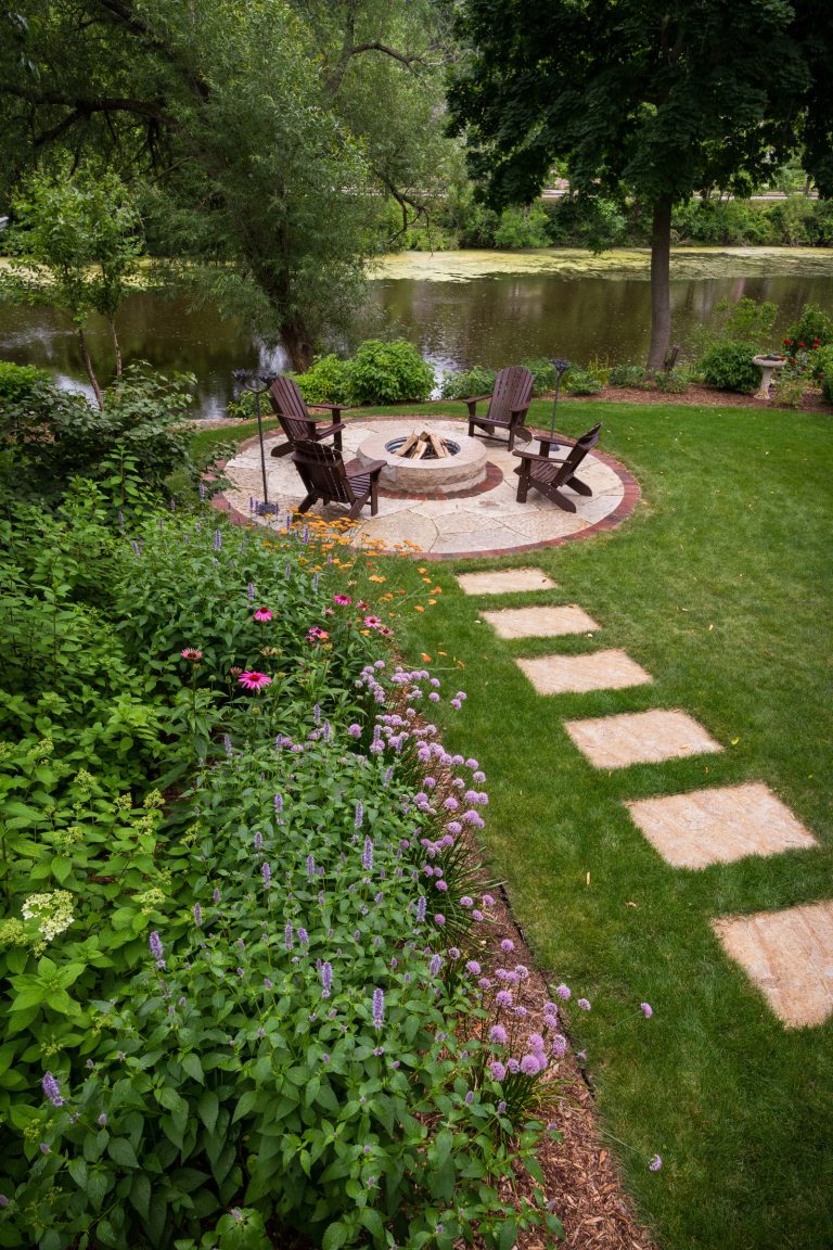 Stone steppers lead to an irregular lannon stone fire pit area in this creekside backyard in Cedarburg, Wisconsin. Westhauser Photography