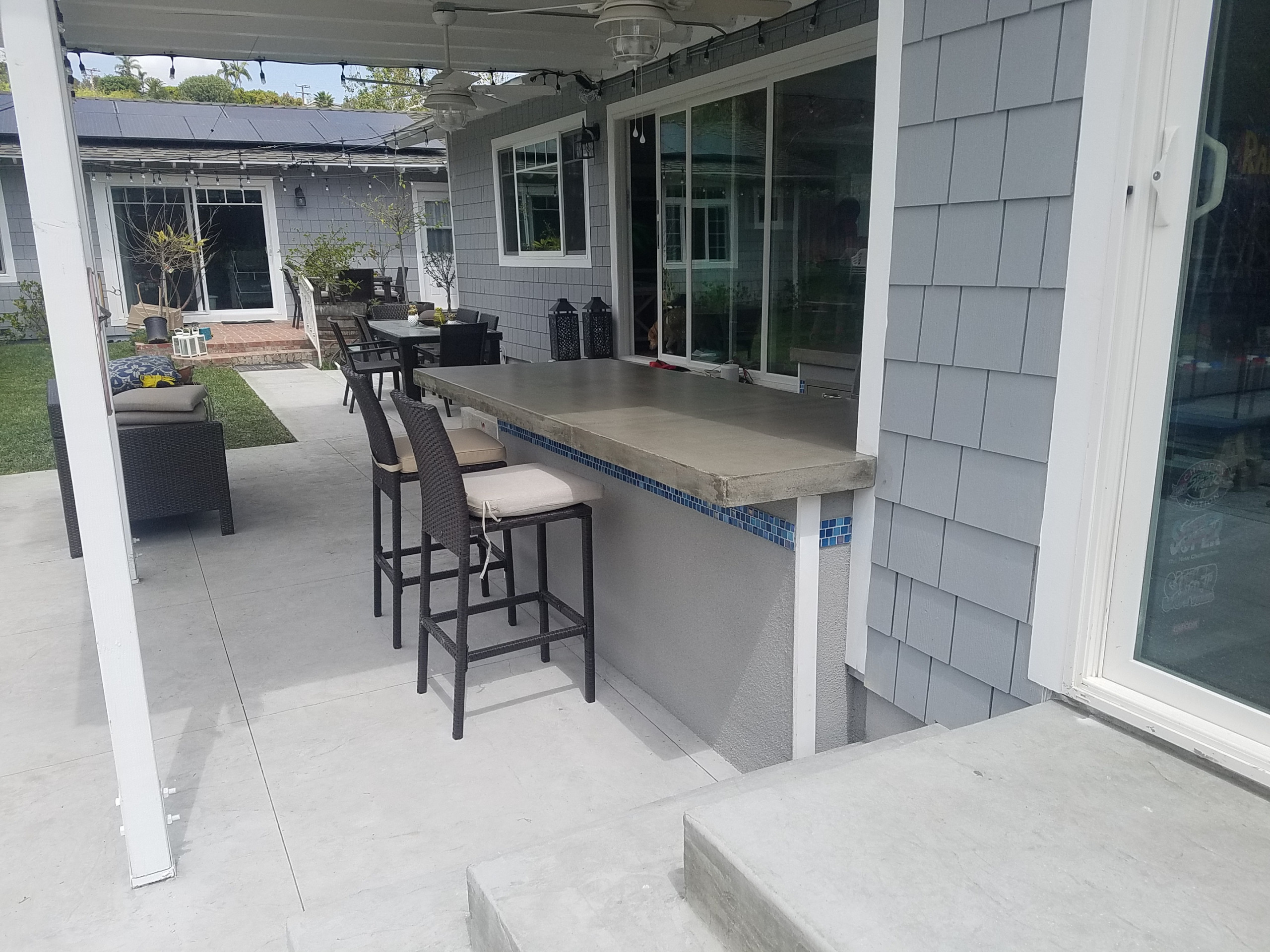 contemporary U-shape island with over hanging bar and mosaic tile strip
Patio kitchen – contemporary backyard patio kitchen idea in Orange County