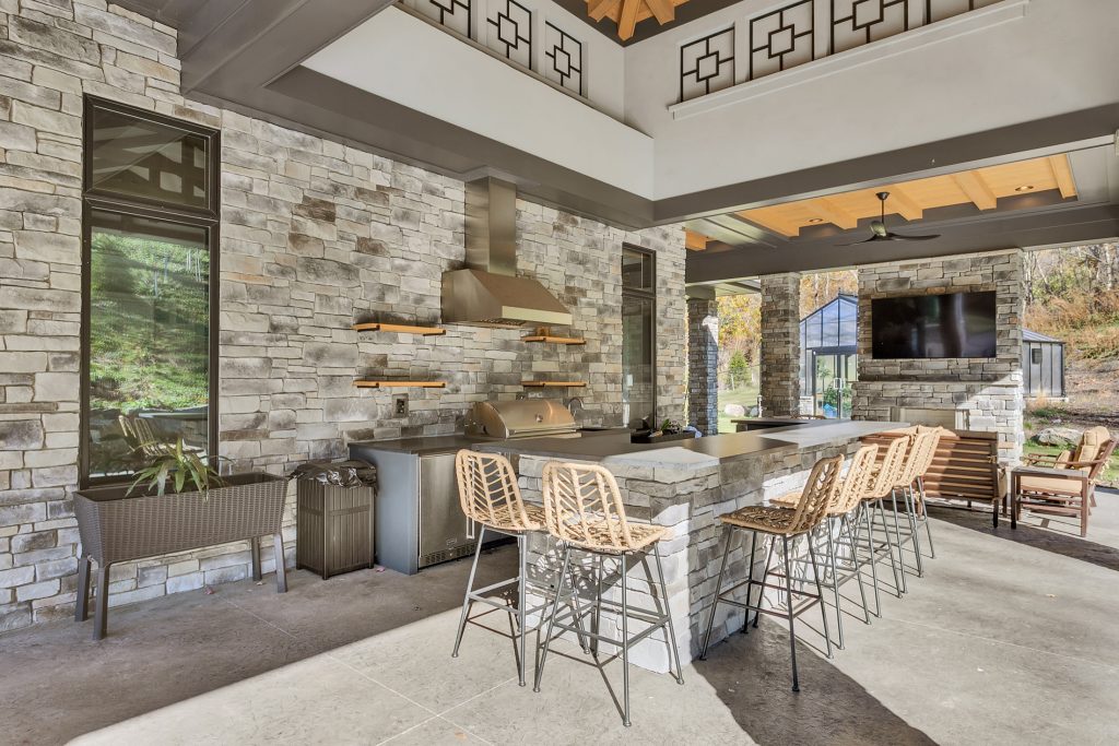 covered rear patio with outdoor kitchen, fireplace and pool