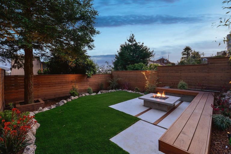 This classic San Francisco backyard was transformed into an inviting and usable outdoor living space. A few steps down lead to a lounging area, featuring drought-friendly and maintenance-free artificial grass as well as a cozy, custom-built natural gas fire pit surrounded by a Redwood bench. Redwood fencing, low-voltage LED landscape lighting, drip irrigation, planting and a water feature completed the space.