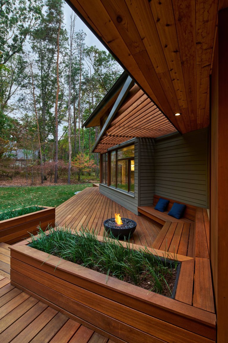 Example of a trendy deck design in Grand Rapids with a fire pit and a roof extension