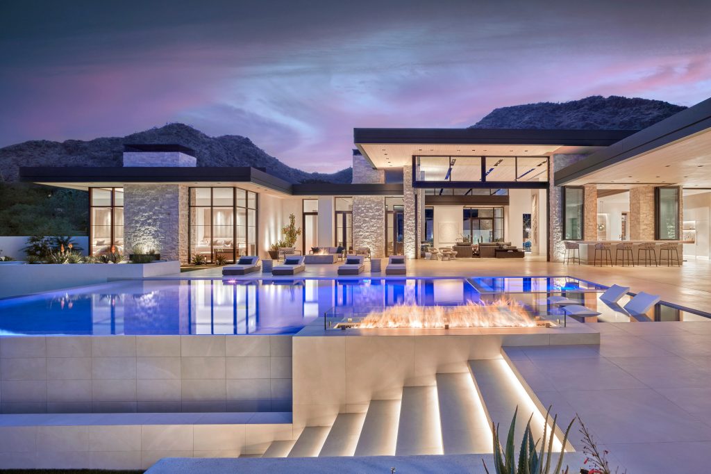 Indoor/outdoor living in the desert doesn't get much better. This award-winning contemporary home opens itself to a gorgeous patio and pool area illuminated to show off its best features. With its brilliant blue pool glow and roaring fire pits, this backyard setting resonates with the warmth of the interiors.

Project // Ebony and Ivory
Paradise Valley, Arizona
Architecture: Drewett Works
Builder: Bedbrock Developers
Interiors: Mara Interior Design - Mara Green
Landscape: Bedbrock Developers
Photography: Werner Segarra
Limestone walls: Solstice Stone

https://www.drewettworks.com/ebony-and-ivory/ by Drewett Works | Pool design | Pool Contracting | Swimming Pool Ideas | Swimming Pool Design Ideas