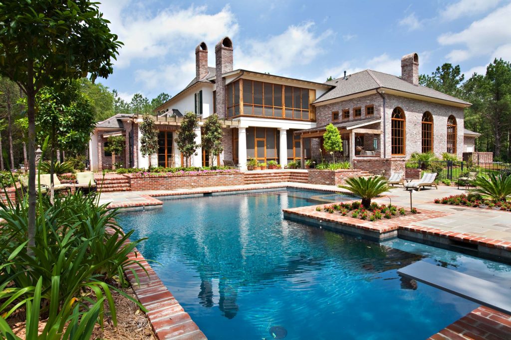 A stunning pool designed and installed by Steve Evans of Waterscapes lies just beyond the outdoor kitchen, screen porch and warehouse/gameroom. Beyond the pool is a red barn recently installed by homeowners. Photography by Mary Ann Elston, Pool by Steve Evans of Waterscapes.