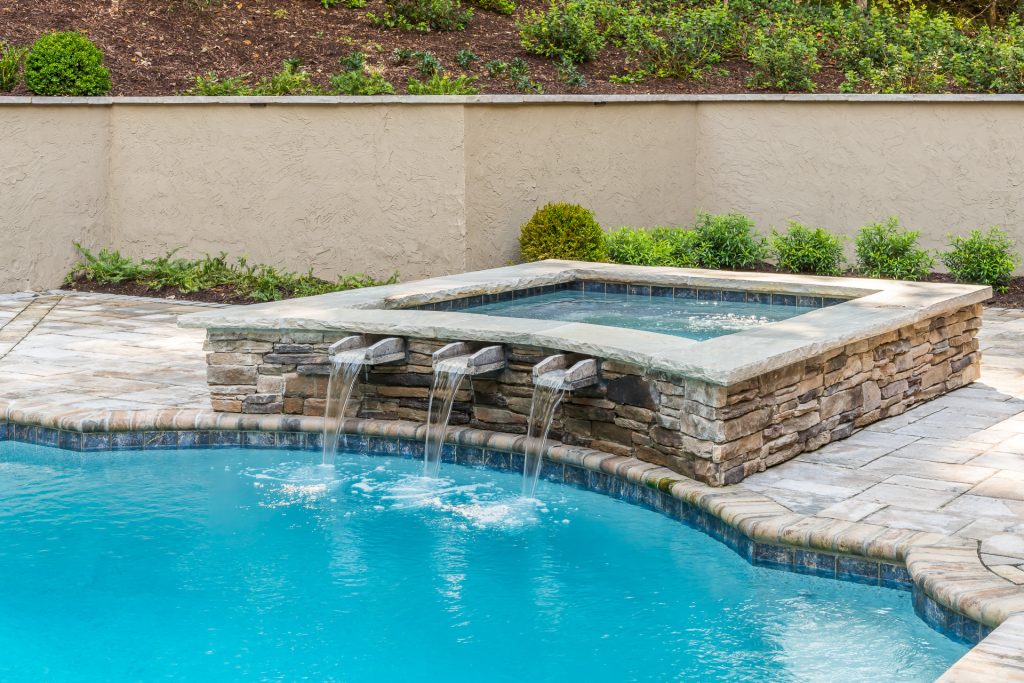 This North Buckhead project included refinishing the pool, adding a spa, and replacing the surround, stairs and existing gazebo. We used the gazebo space to create an outdoor kitchen and lounge pavilion, and we added a putting green.T he style combines the sophistication of the large Buckhead home with it’s beautiful woodsy surroundings. Stone is prominent throughout the pavilion/gazebo, adding a bit of rustic style. The vaulted ceiling is composed of rich cedar boards and contains plenty of lights that can be adjusted for the mood.