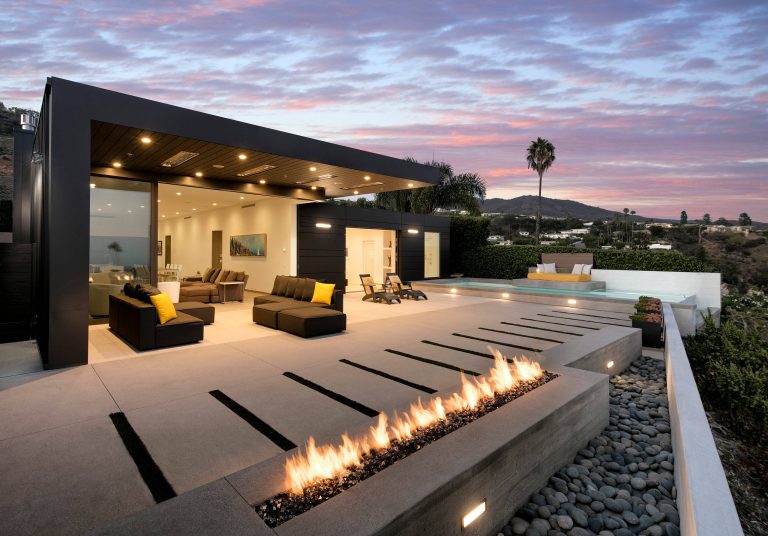 On the patio, an infinity pool overlooks the Pacific Ocean below. A low profile fire pit is paired with shorter succulents to maintain a direct view. Photo: Jim Bartsch
