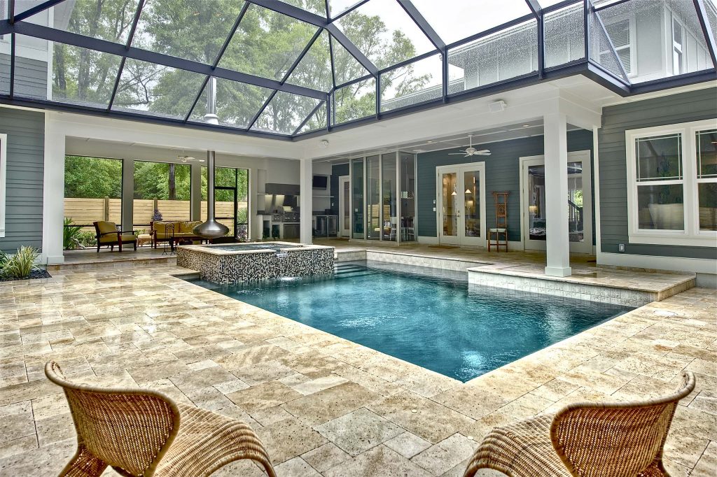 Screened in backyard pool & hot tub with travertine pavers deck. FireOrb next to tub and outdoor kitchen/grill. Main house to the left with Garage and 2nd floor Guest Suite to the left. Photo by Aaron Bailey Photography - awbailey.com