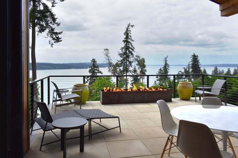 Panorama views from a modern deck featuring a linear fire table, stainless steel cable railing and waterproof pedestal concrete decking.