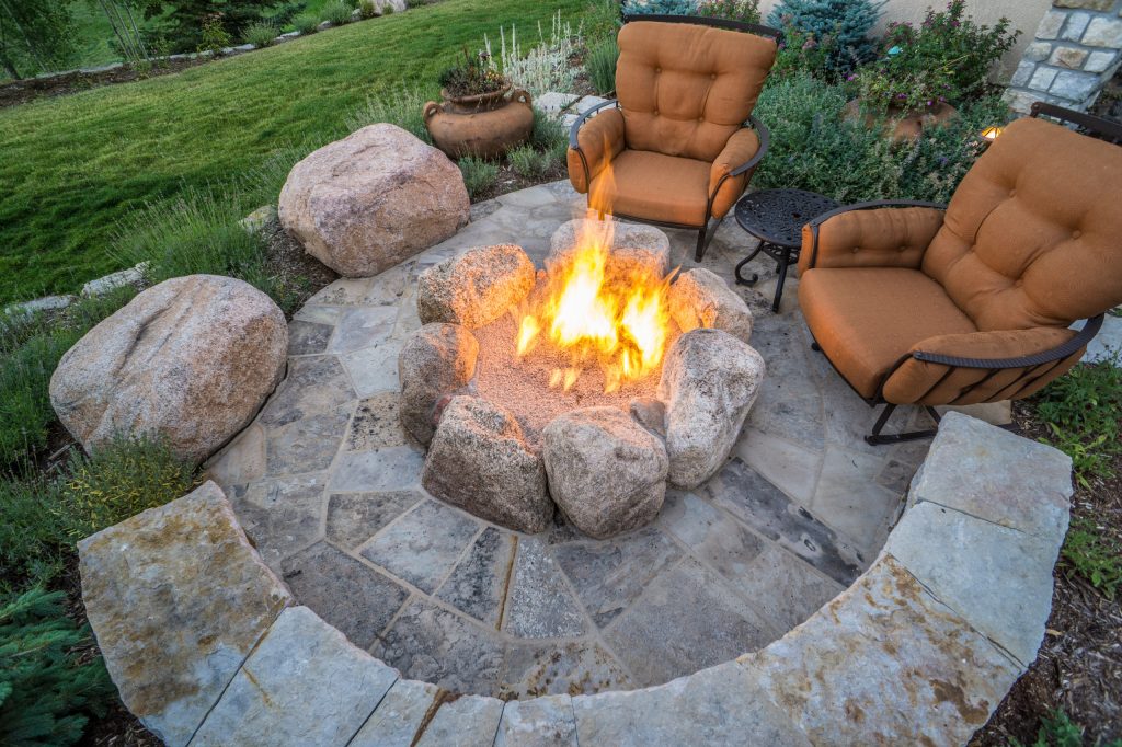 This stunning patio is constructed of all natural and local materials. The patio itself is Colorado Buff flagstone, the bench is built of Siloam stone, and the seating boulders and natural gas fire pit are Broadmoor boulders