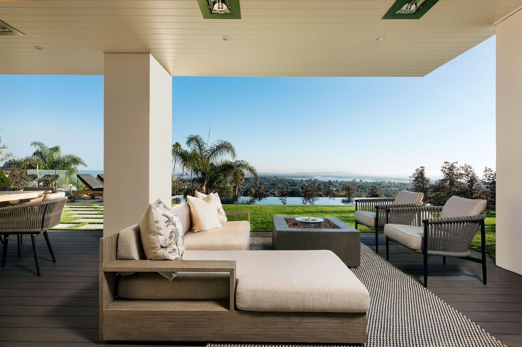 Example of a large beach style backyard patio design in San Diego with a fire pit, decking and a roof extension