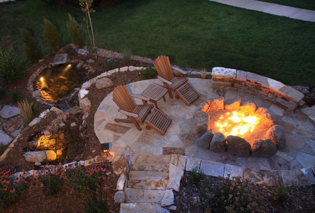 This natural gas fire pit is the perfect place for entertaining, offering built in natural stone bench seating, natural boulder seating, and room for chairs. The water feature adds to the ambiance, providing the tranquil sound of a natural creek.