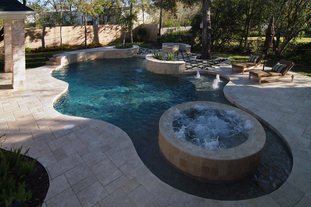 After enjoying a dip in the pool, guests can gather around the fire pit that has a built-in bench nestled behind. The deep end of the pool has a raised wall that doubles as a diving/jumping platform. Bubbler fountains adorn a tanning platform, while sheer descent waterfalls flow over a built-in planter. by User | Pool design | Pool Contracting | Swimming Pool Ideas | Swimming Pool Design Ideas