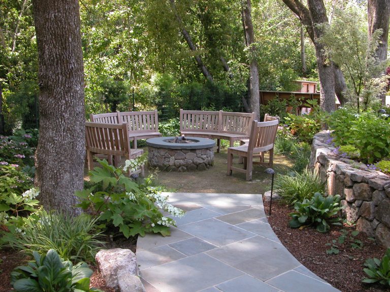 A stone fire pit with circular seating with teak benches photo by Galen Fultz