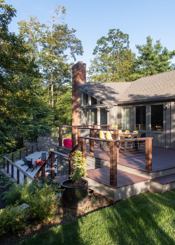 Created a multi-level outdoor living space to match the mid-century modern style of the home with upper deck and lower patio. Porcelain pavers create a clean pattern to offset the modern furniture, which is neutral in color and simple in shape to balance with the bold-colored accents. by Amy Martin Landscape Design | Fire Pits|Backyard Design|Outdoor Living Spaces|Landscape Design|Backyard Ideas|Landscaping|Landscaping Ideas|Landscape Installation|Fire Feautures|Fire Pit