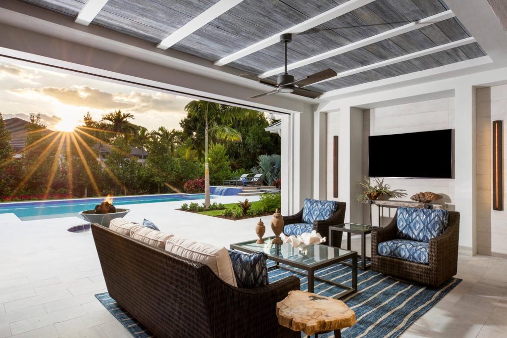 Example of a large beach style backyard stone patio design in Miami with a fire pit and a roof extension