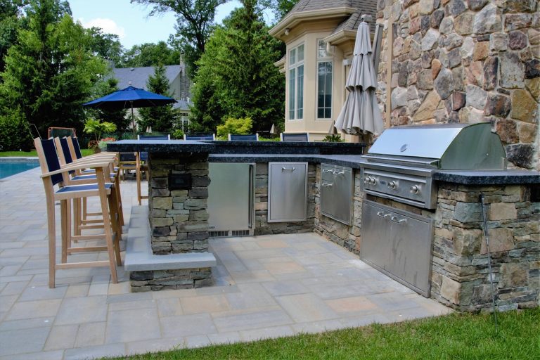 outdoor kitchen with ample bar seating and stainless steel appliances