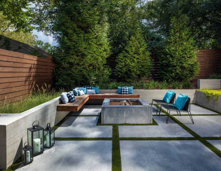 This inviting space features a decorative concrete patio with a custom concrete fire pit and Ipe floating bench. The lush landscaping and cedar privacy fence provides a tranquil setting for city living.