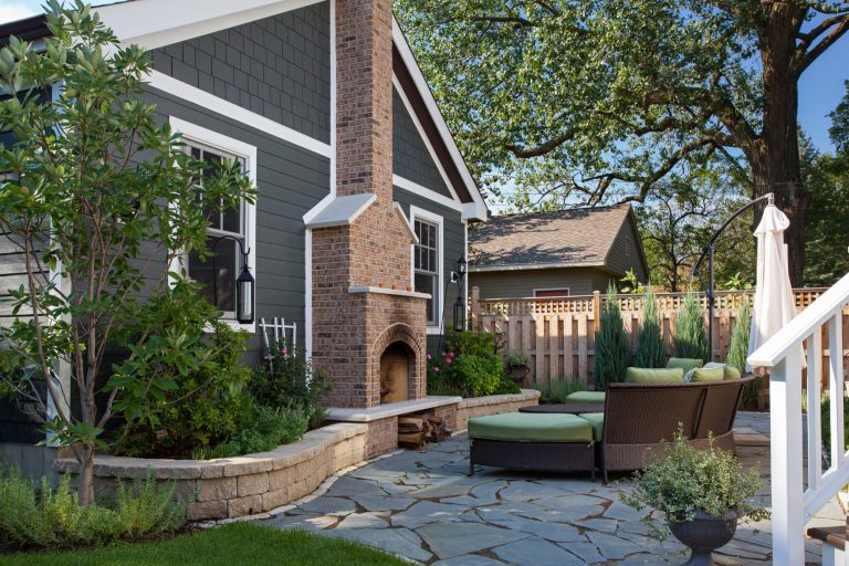 Outdoor living space with patio fireplace and beautiful garden landscaping consisting of flowers, Roses, bushes, shrubs, large mature oak trees, and various plants incased by brick pavers. The luxury custom home builder set the ground with natural slate stone tiles. Others include outdoor furniture, and stained wooded fence, cedar deck, cedar shake shingles and planks – a backyard retreat paradise. Contact Miller + Miller if you're looking for real estate agents who specialize in luxury properties. Ryan & Sarah Miller are licensed real estate brokers & Realtors.

Custom Home Builder and General Contractor for this Home:
Leinster Construction, Inc., Chicago, IL
www.leinsterconstruction.com

Miller + Miller Architectural Photography by MILLER + MILLER Architectural Photography | Fire Pits|Backyard Design|Outdoor Living Spaces|Landscape Design|Backyard Ideas|Landscaping|Landscaping Ideas|Landscape Installation|Fire Feautures|Fire Pit