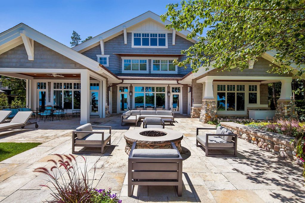 Inspired by the surrounding landscape, the Craftsman/Prairie style is one of the few truly American architectural styles. It was developed around the turn of the century by a group of Midwestern architects and continues to be among the most comfortable of all American-designed architecture more than a century later, one of the main reasons it continues to attract architects and homeowners today. Oxbridge builds on that solid reputation, drawing from Craftsman/Prairie and classic Farmhouse styles. Its handsome Shingle-clad exterior includes interesting pitched rooflines, alternating rows of cedar shake siding, stone accents in the foundation and chimney and distinctive decorative brackets. Repeating triple windows add interest to the exterior while keeping interior spaces open and bright. Inside, the floor plan is equally impressive. Columns on the porch and a custom entry door with sidelights and decorative glass leads into a spacious 2,900-square-foot main floor, including a 19 by 24-foot living room with a period-inspired built-ins and a natural fireplace. While inspired by the past, the home lives for the present, with open rooms and plenty of storage throughout. Also included is a 27-foot-wide family-style kitchen with a large island and eat-in dining and a nearby dining room with a beadboard ceiling that leads out onto a relaxing 240-square-foot screen porch that takes full advantage of the nearby outdoors and a private 16 by 20-foot master suite with a sloped ceiling and relaxing personal sitting area. The first floor also includes a large walk-in closet, a home management area and pantry to help you stay organized and a first-floor laundry area. Upstairs, another 1,500 square feet awaits, with a built-ins and a window seat at the top of the stairs that nod to the home’s historic inspiration. Opt for three family bedrooms or use one of the three as a yoga room; the upper level also includes attic access, which offers another 500 square feet, perfect for crafts or a playroom. More space awaits in the lower level, where another 1,500 square feet (and an additional 1,000) include a recreation/family room with nine-foot ceilings, a wine cellar and home office.

Photographer: Jeff Garland by Visbeen Architects | Fire Pits|Backyard Design|Outdoor Living Spaces|Landscape Design|Backyard Ideas|Landscaping|Landscaping Ideas|Landscape Installation|Fire Feautures|Fire Pit