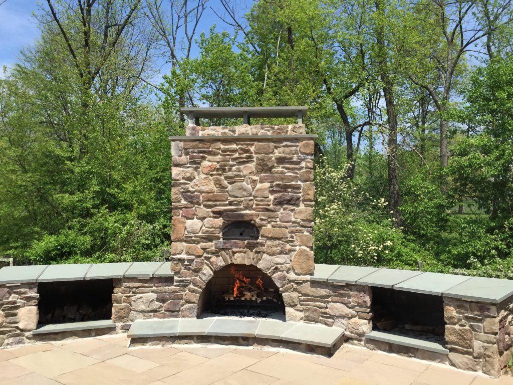 Example of a large mountain style backyard stone patio design in Philadelphia with a fire pit and no cover