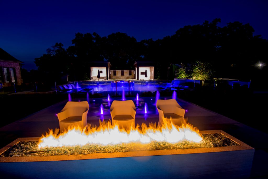 Fun, sleek, modern pool with amazing features: cabana, fire bar, splash pad with LED lights, long dolphin slide, outdoor kitchen with retractable doors and a secret garden/play area for the kids. Photos by Farley Designs.
