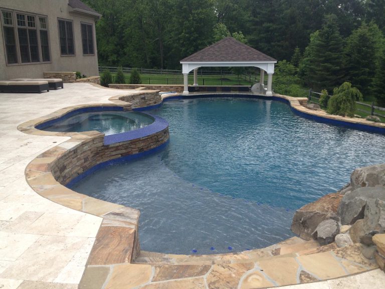 pool with stone coping and travertine patio