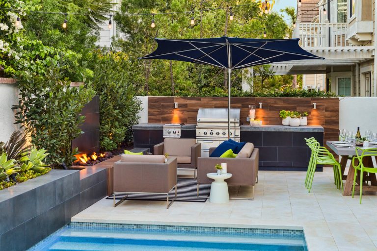 Poolside fire pit and barbecue with dining area. Stone limestone pavers with porcelain veneer throughout. Studio H Landscape Architecture