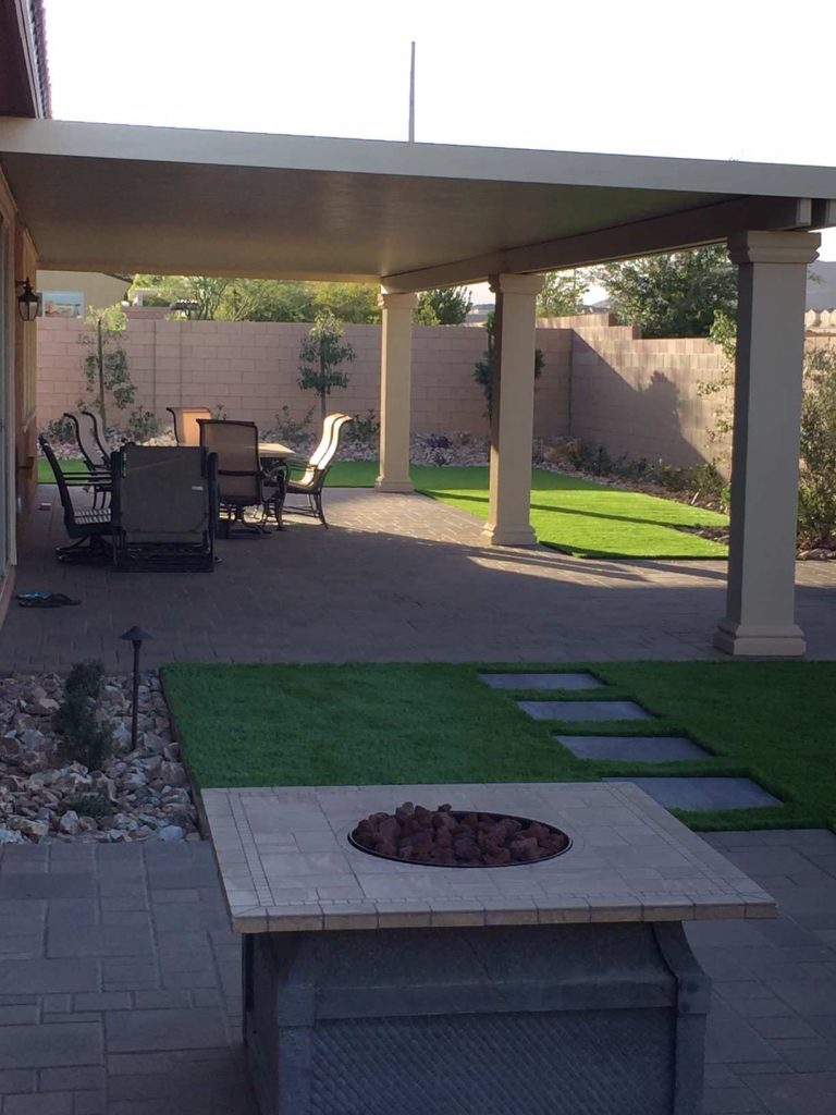 Inspiration for a mid-sized timeless backyard brick patio remodel in Las Vegas with a fire pit and a roof extension