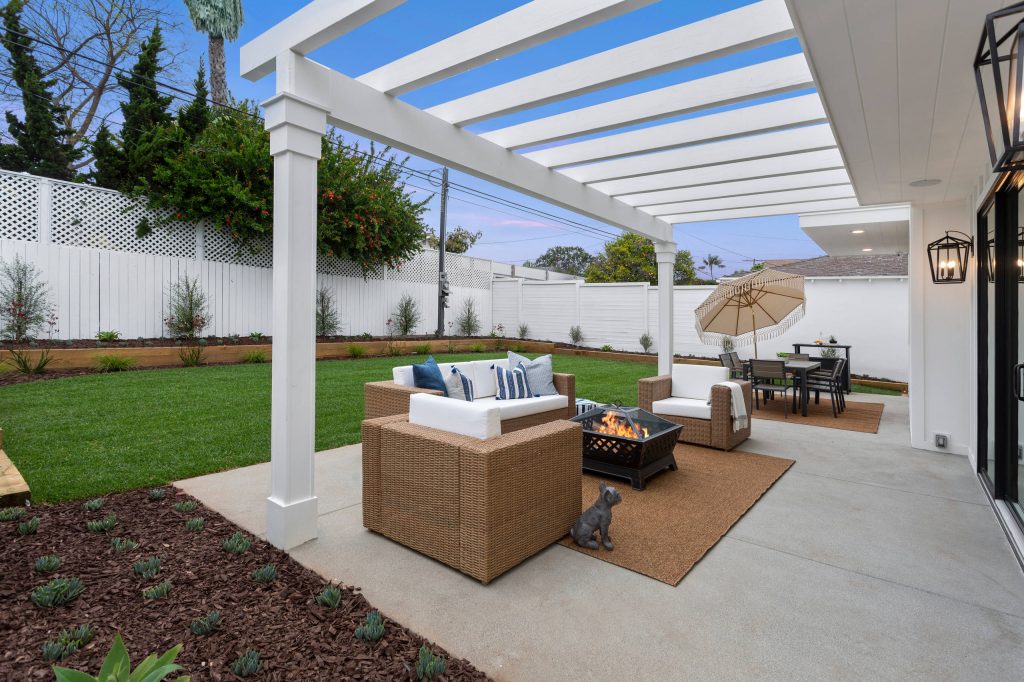 Example of a transitional backyard concrete paver patio design in Los Angeles with a fire pit and a pergola