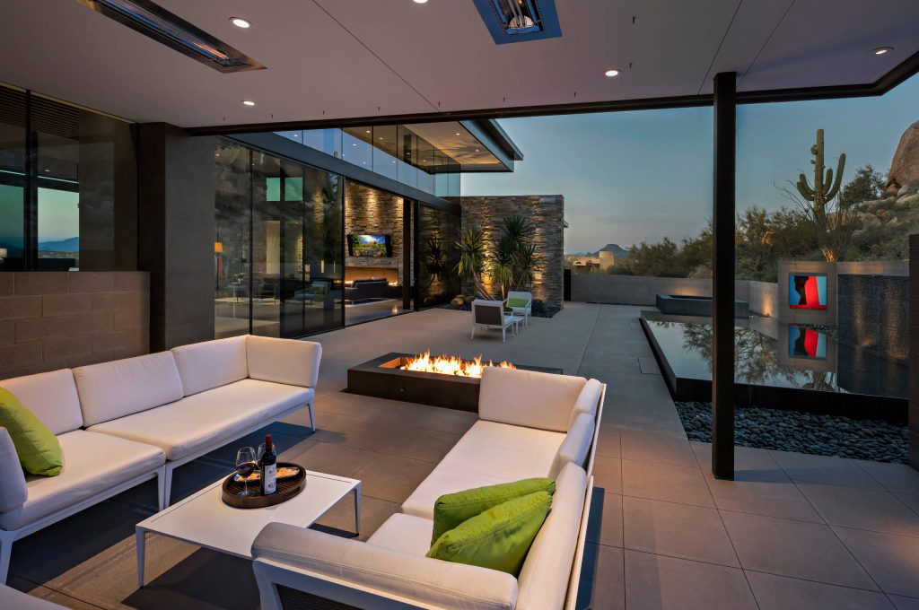 Shaded seating area on the back patio with a firepit to enjoy both warm sunny days and cool evenings. The reflecting pool adds a beautiful calm backdrop to the backyard experience. Builder - Build Inc, Interior Design - Tate Studio Architects, Landscape - Desert Foothills Landscape, Photography - Thompson Photographic. by Tate Studio Architects | Fire Pits|Backyard Design|Outdoor Living Spaces|Landscape Design|Backyard Ideas|Landscaping|Landscaping Ideas|Landscape Installation|Fire Feautures|Fire Pit