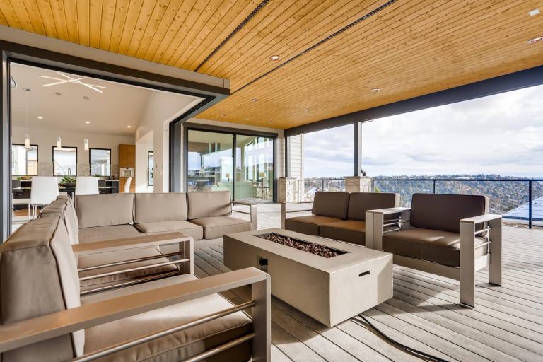 Example of a large trendy deck design in Denver with a fire pit and a roof extension