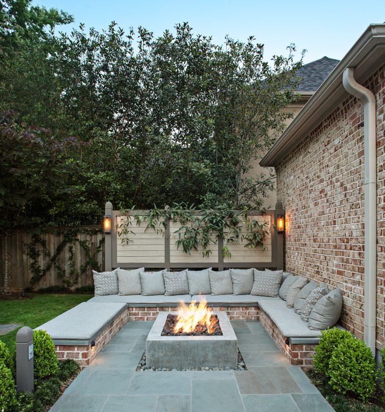 Built-in custom polished concrete fire -pit with surrounding brick bench with a bluestone cap. Bluestone patio paving with slot of gray beach pebbles. Fire-pit has natural gas with an electric spark starter. Bench seating has a wood screen wall that includes lighting & supports vine growth.