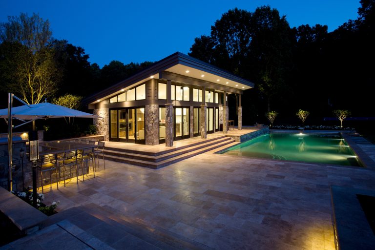 Modernism and traditionalism are just steps away from each other at this Vienna Virginia pool house. The main house, built by a national homebuilder, draws upon tradition, but the pool house, speaks the language of contemporary minimalism. It presents clean lines and a soaring roofline overhanging tall glass doors and clerestory windows. Great design, careful attention to detail, first-rate materials and impeccable craftsmanship have yielded a spectacular solution for outdoor entertaining. With a fireplace and every conceivable convenience under roof, this pool house might just be the perfect escape for inclement weather as well. Photography by Greg Hadley http://www.greghadleyphotography.com